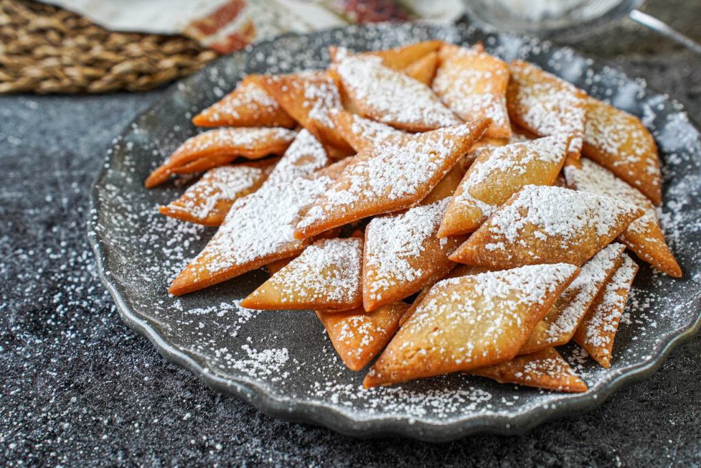 A pile of Sakar Para on a gray plate with a dusting of powdered sugar.
