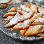 A pile of Sakar Para on a gray plate and covered with powdered sugar.