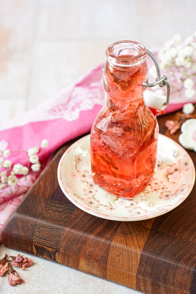 Close up of Cherry Blossom Syrup in a glass jar on a cherry blossom plate.