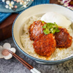 Three Chicken Meatballs (Tsukune) in a bowl with rice, bok choy sprouts, and a poached egg.