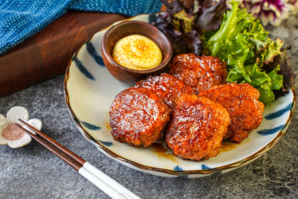 Five Tsukune (Chicken Meatballs) on a plate with mayonnaise and lettuce.