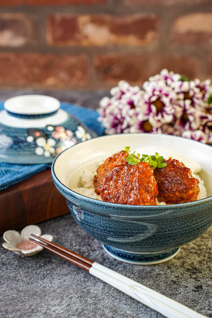 Side view of three Tsukune (Chicken Meatballs) in a bowl with rice.