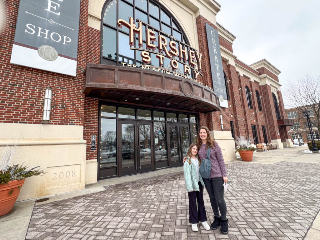 Mother and daughter smiling in front of The Hershey Story.