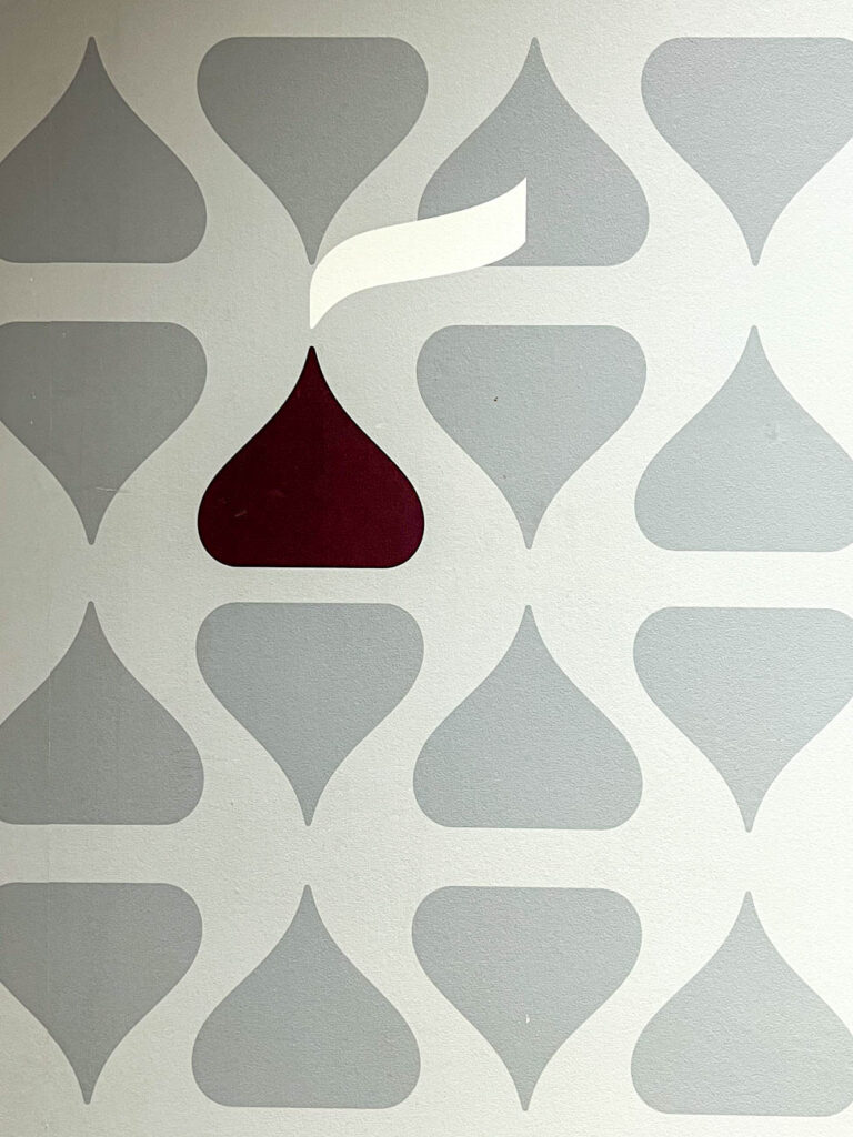 Photo of a wall of gray Hershey kisses with one brown kiss.