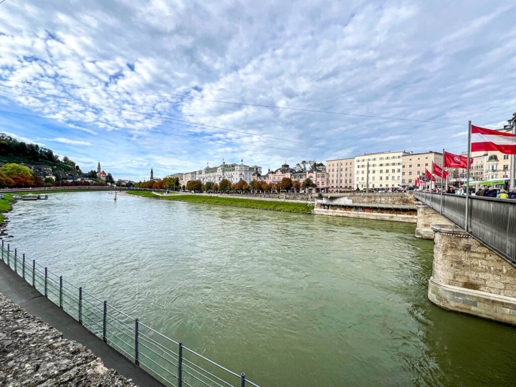 River in Salzburg with Austrian flag on the right over a bridge.