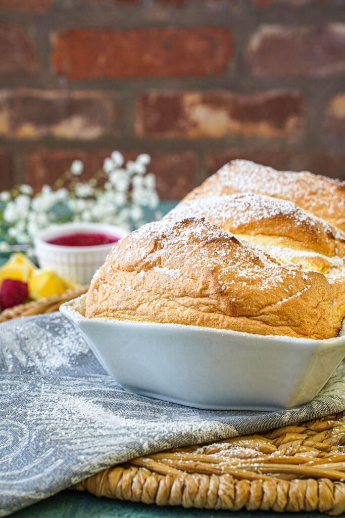 Salzburger Nockerl in a white baking dish with raspberry sauce and white flowers in the background.