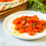 Vichy Carrots (Carottes Vichy) on a white plate with chopped parsley.