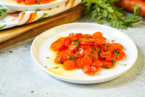 Vichy Carrots (Carottes Vichy) on a white plate with chopped parsley.