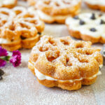 Baci Panteschi (Flower-Shaped Ricotta-Filled Pastries) next to pink flowers and chocolate chips.