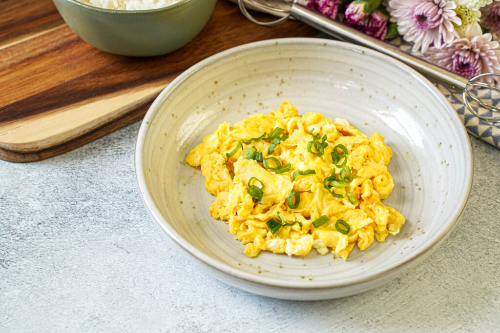 Miso Scrambled Eggs in a bowl with thinly sliced green onions.