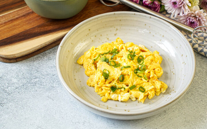 Miso Scrambled Eggs in a bowl with thinly sliced green onions.