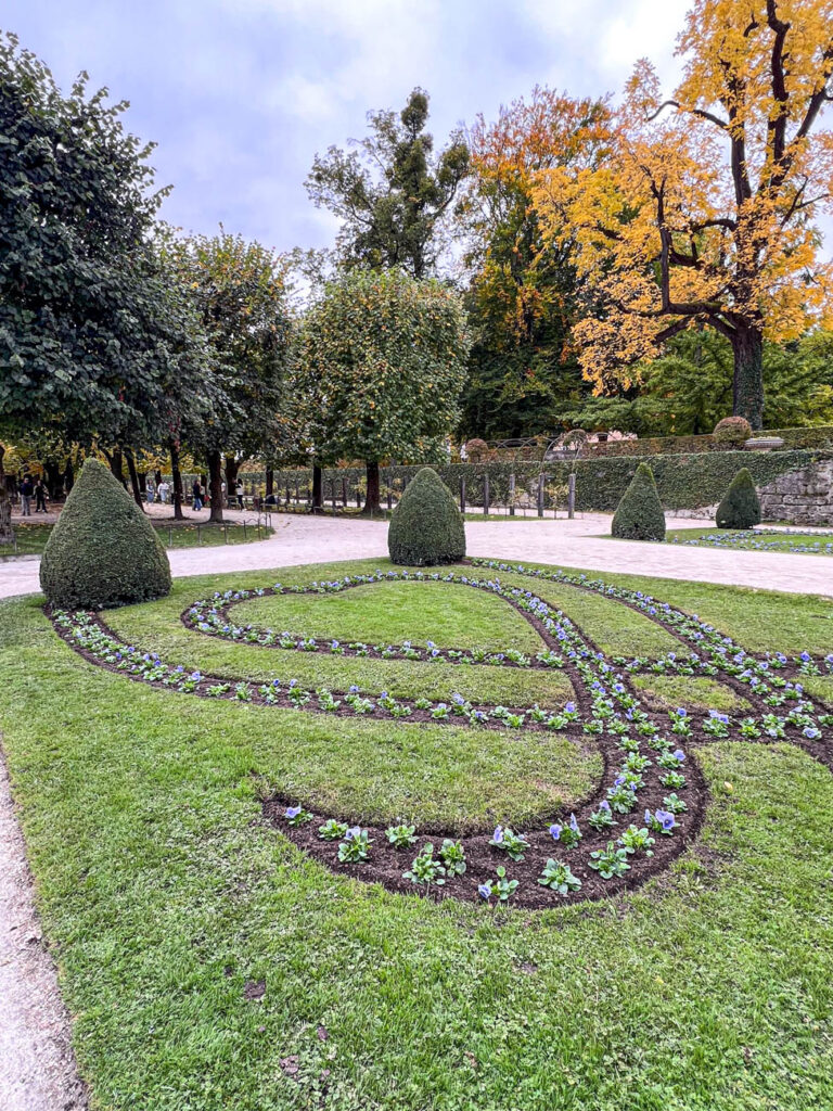 Purple flowers and green triangular hedges at Mirabell Garden.