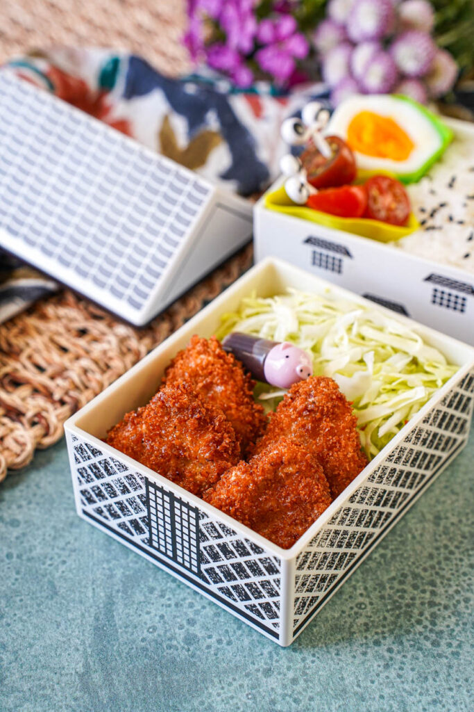Close up of Mini Pork Cutlets in a bento with shredded cabbage.