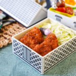Mini Pork Cutlets in a house-shaped bento with shredded cabbage, rice, tomatoes, and half an egg.