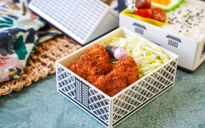 Mini Pork Cutlets in a house-shaped bento with shredded cabbage, rice, tomatoes, and half an egg.
