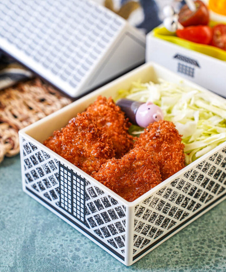 Mini Pork Cutlets in a house-shaped bento with shredded cabbage, rice, tomatoes, and half an egg.