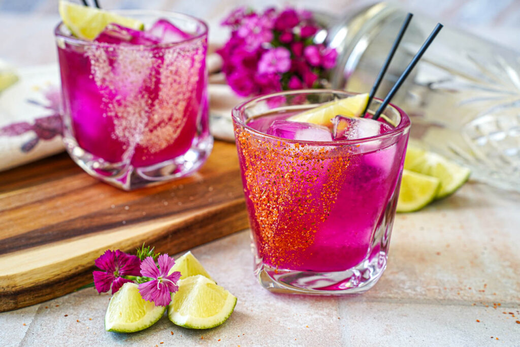 Prickly Pear Margarita in two glasses with tajin and sea salt rims.