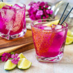 Prickly Pear Margarita in two glasses with tajin and salt rims.