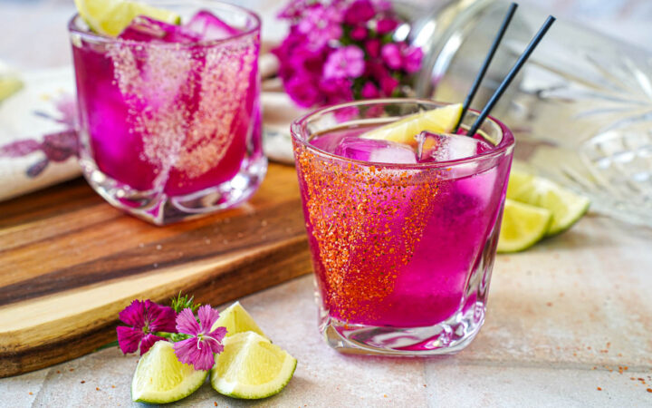 Prickly Pear Margarita in two glasses with tajin and salt rims.