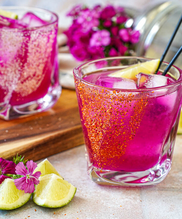 Prickly Pear Margarita in two glasses with tajin and salt rims.