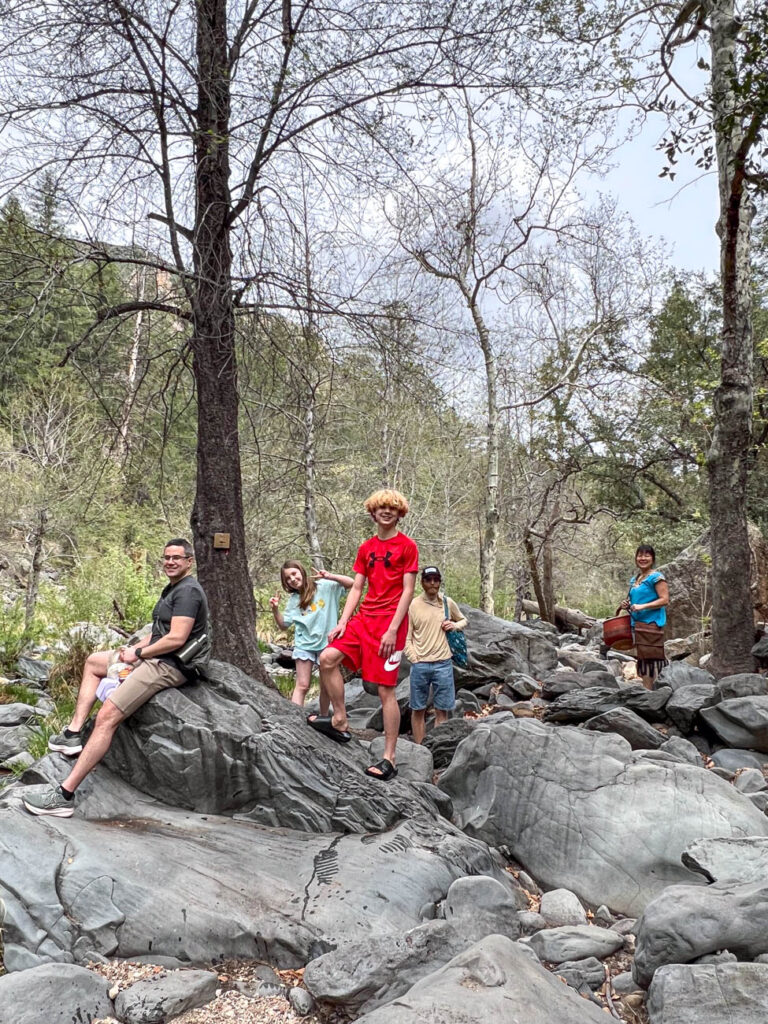 Five people sitting and standing on rocks and smiling.