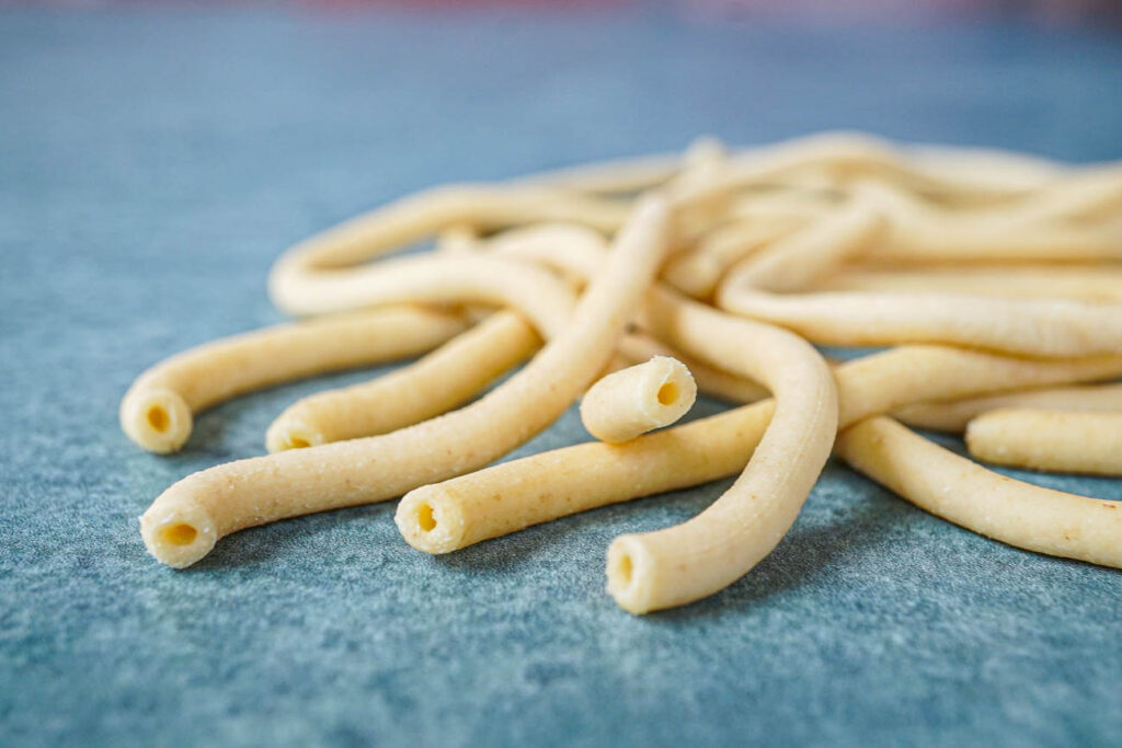 Fresh Bucatini noodles on a green background.
