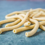 Bucatini noodles on a green background.