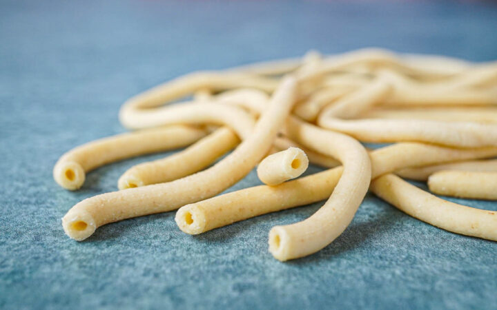 Bucatini noodles on a green background.