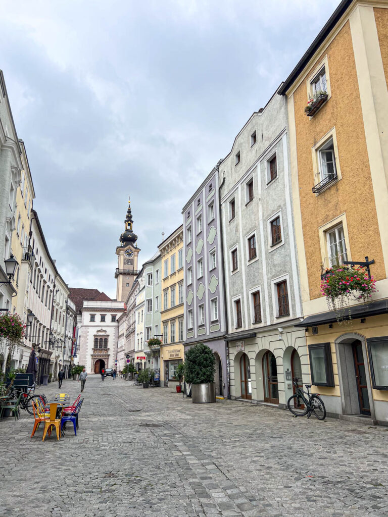 Orange, grey, and purple houses along a cobblestone street in Linz.