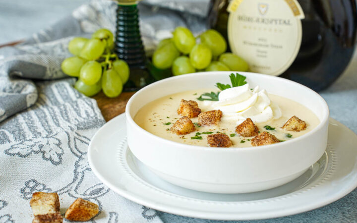 Fränkische Weinsuppe (Franconian Wine Soup) in a white bowl with cream, parsley, and cinnamon croutons.
