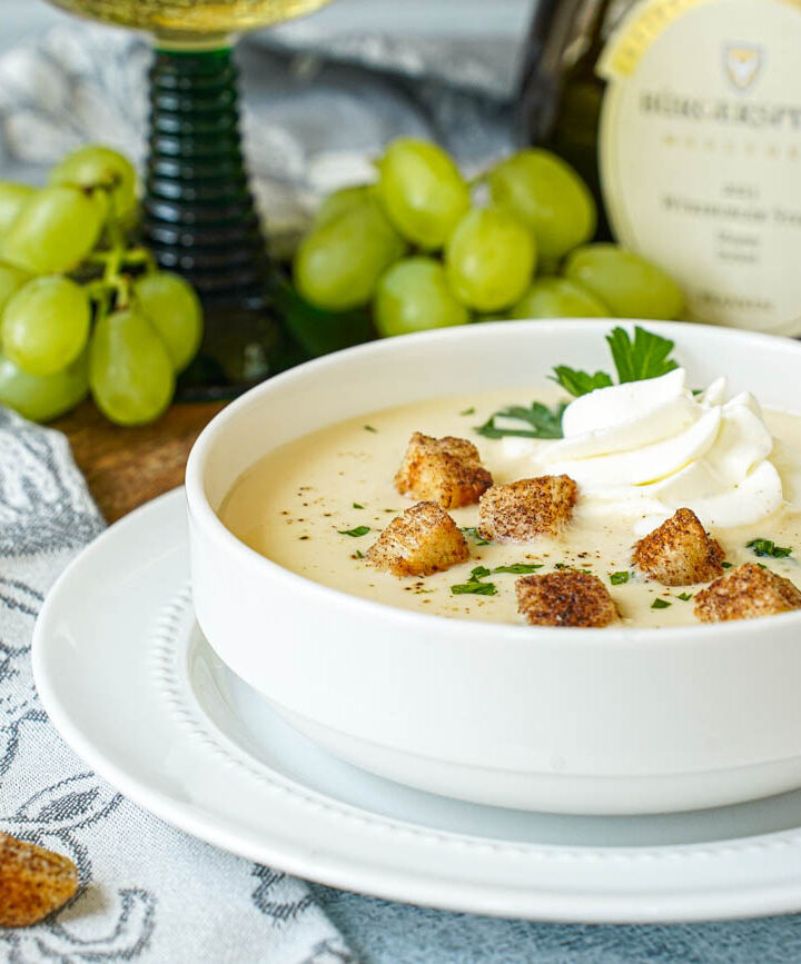 Fränkische Weinsuppe (Franconian Wine Soup) in a white bowl with cream, parsley, and cinnamon croutons.