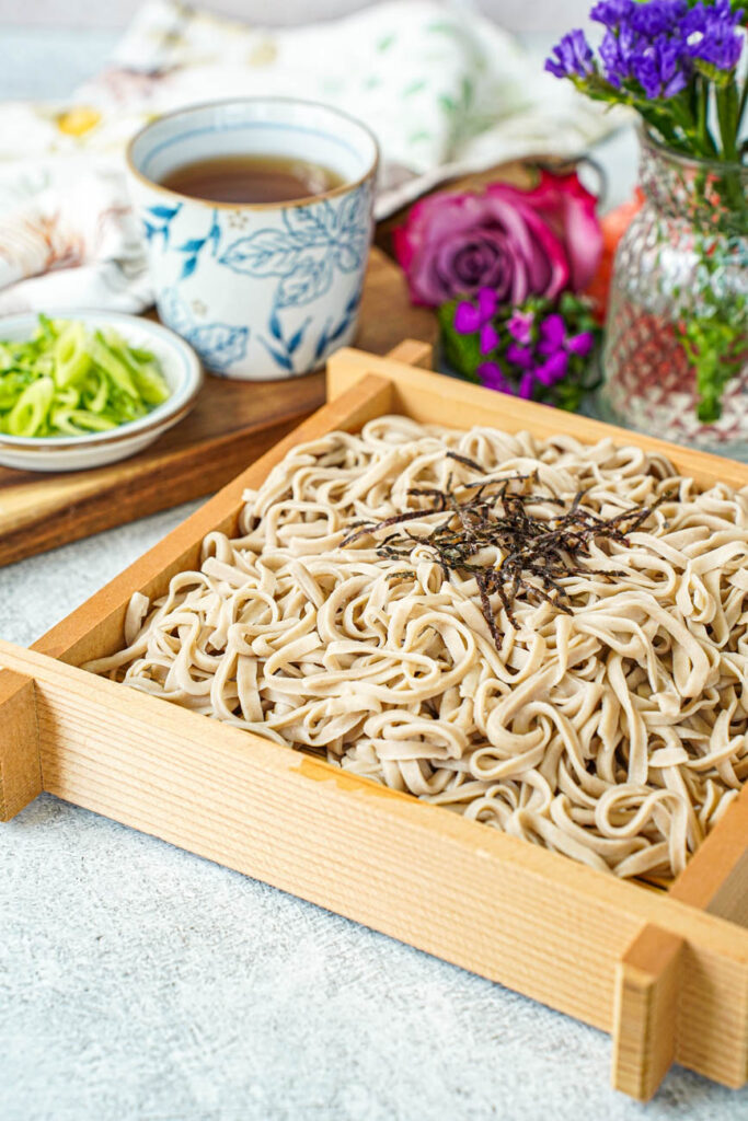 Homemade Soba in a square wooden box with shredded seaweed.