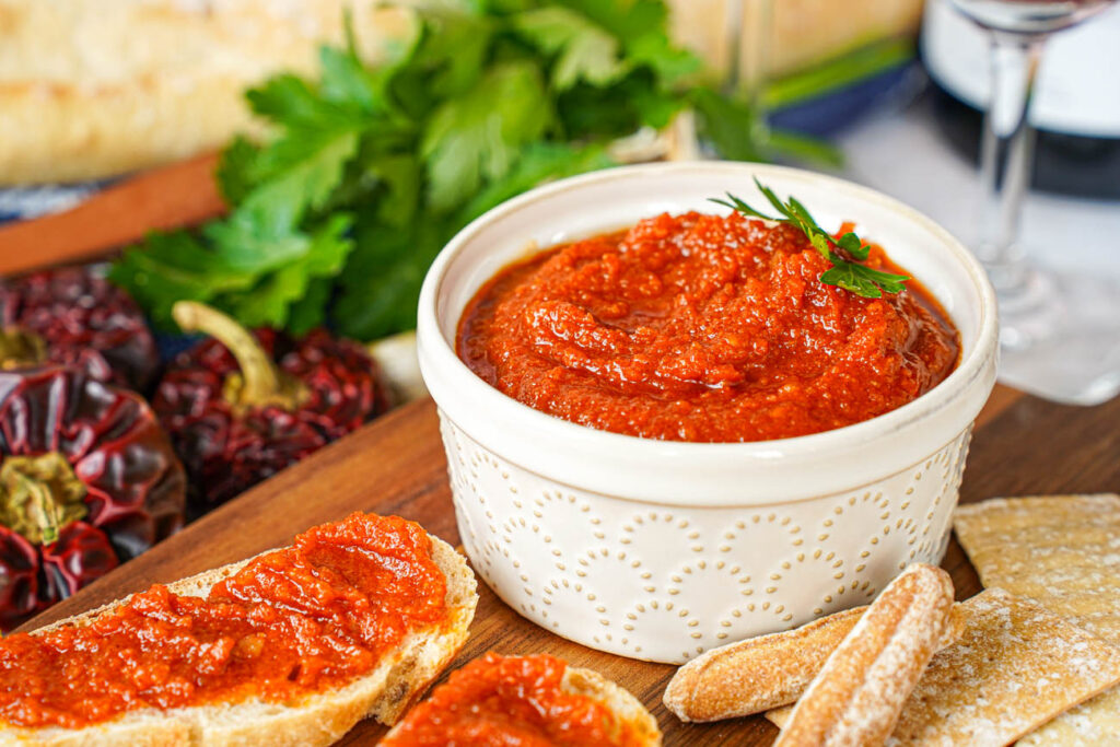 Almogrote (Canarian Cheese Pâté) in a ramekin with parsley and peppers in the background.