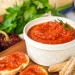 Almogrote (Canarian Cheese Pâté) in a ramekin next to crackers and bread slices topped with the cheese.