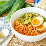 Korean Cucumber Salad Ramyeon in a white bowl with a halved egg.