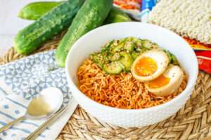 Korean Cucumber Salad Ramyeon in a white bowl with a halved egg.