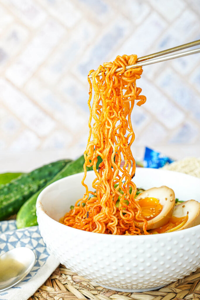 A pair of chopsticks holding up noodles.