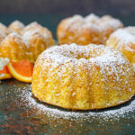 Four small Meskouta (Moroccan Orange Cakes) covered in powdered sugar.