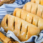 Pão com Chouriço (Portuguese Chouriço Bread) in a basket with a grey and white striped towel.