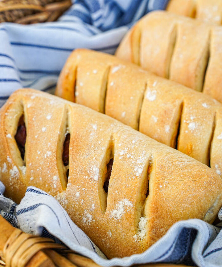Pão com Chouriço (Portuguese Chouriço Bread) in a basket with a grey and white striped towel.