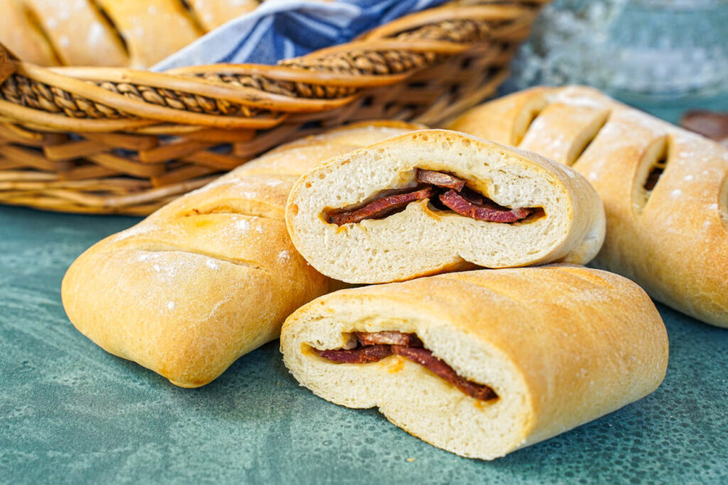 Three Pão com Chouriço (Portuguese Chouriço Bread) with one cut in half to show chouriço slices.