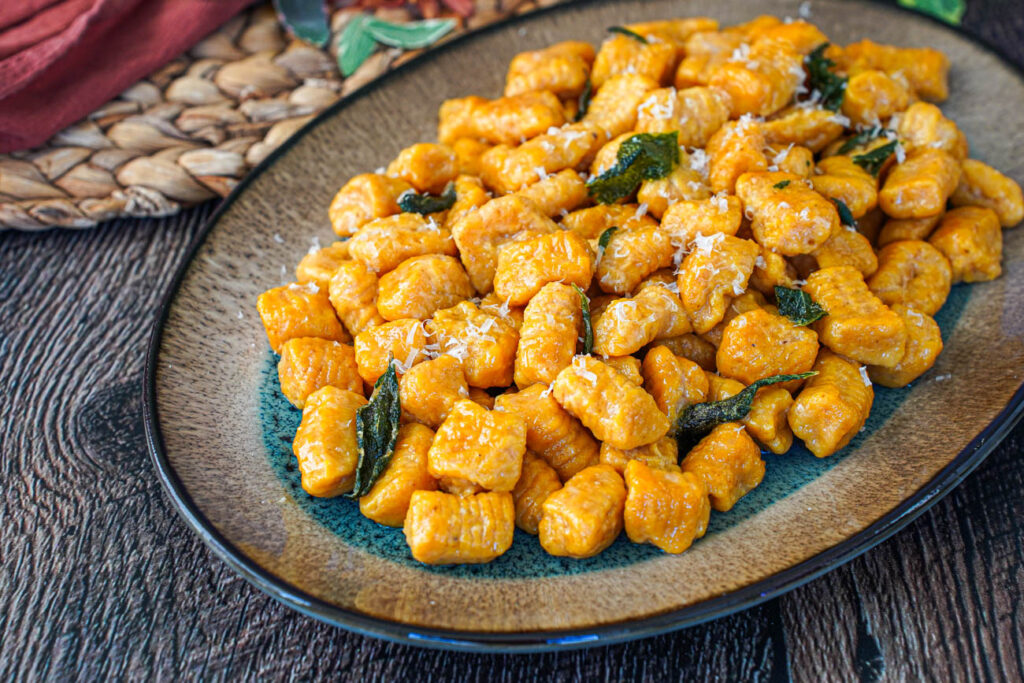 Pumpkin Ricotta Gnocchi on an oval plate with fried sage leaves.