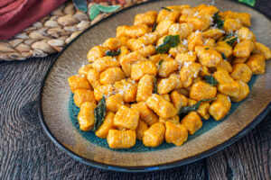 Pumpkin Ricotta Gnocchi on an oval tray with crisp sage leaves.