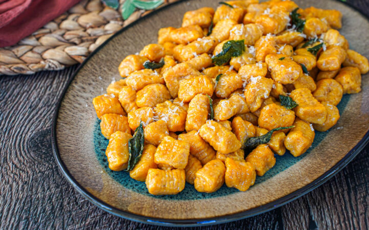 Pumpkin Ricotta Gnocchi on an oval tray with crisp sage leaves.