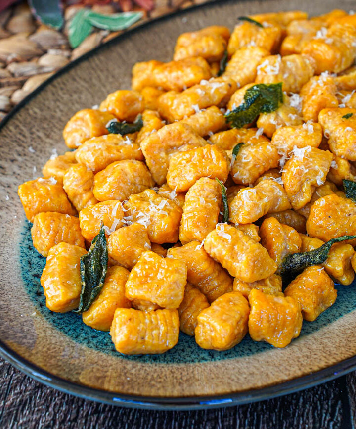 Pumpkin Ricotta Gnocchi on an oval tray with crisp sage leaves.
