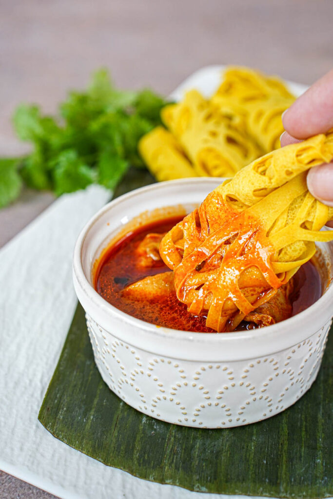 Dipping a Roti Jala into a bowl of chicken curry.