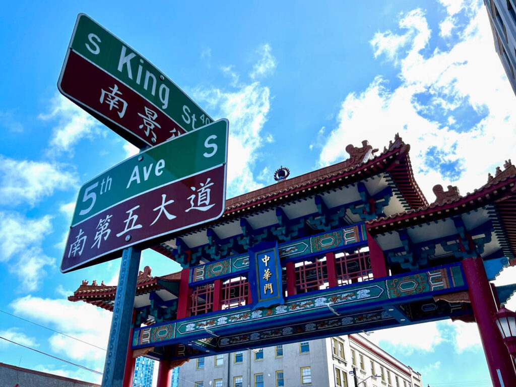 Sign for S King Street and 5th Avenue South with translation in Chinese and Chinese gate in background.