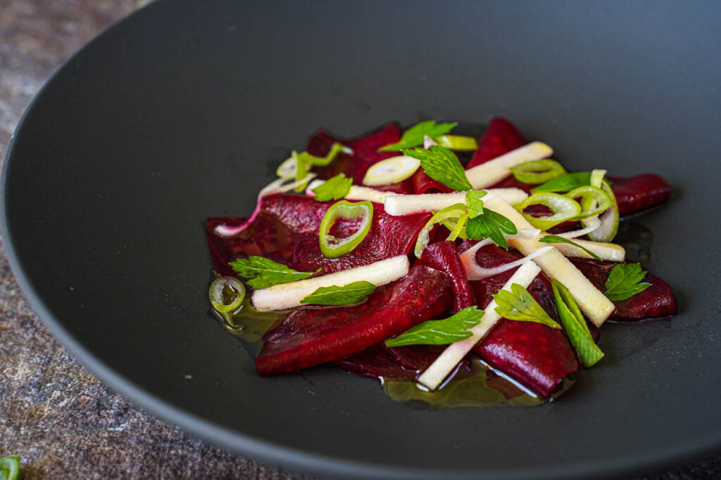 Close up of Tangy Beetroot Salad in a black bowl.