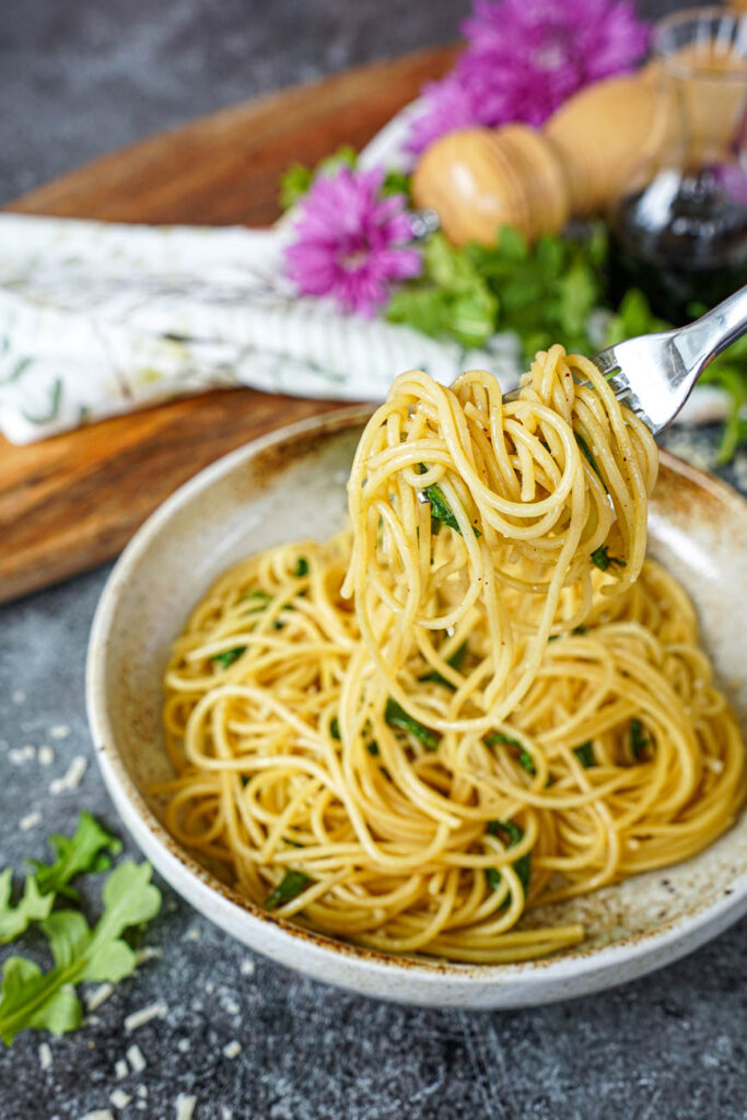 A fork lifting Spaghetti with Balsamic Butter from a tan bowl.